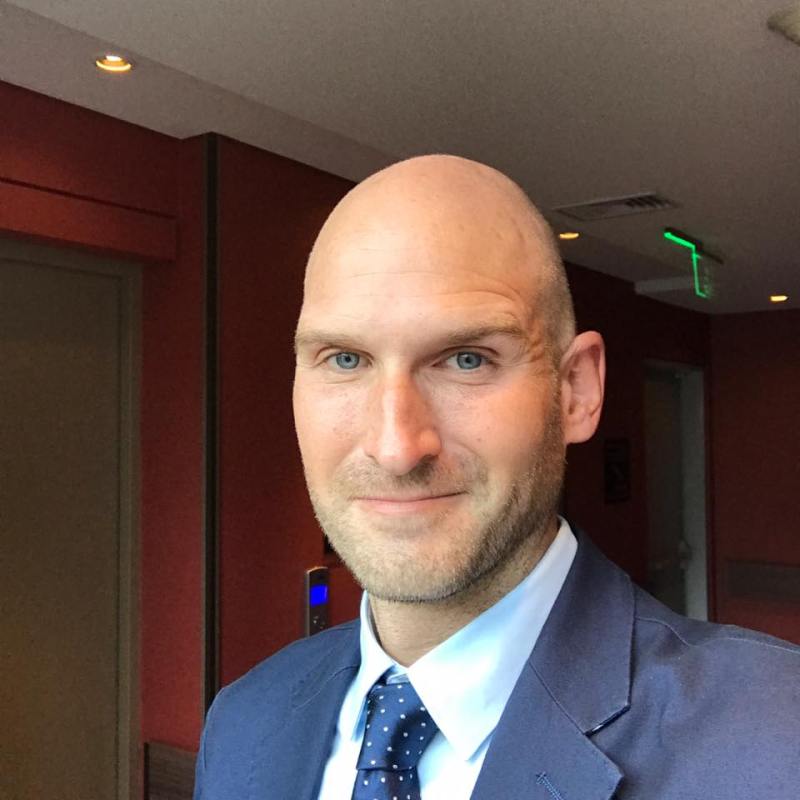 a man wearing a suit and tie smiling at the camera