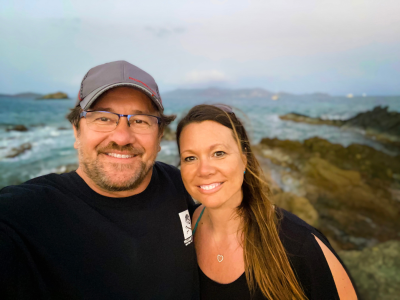 a man and a woman standing in front of a body of water