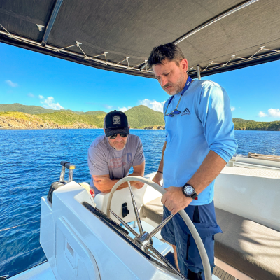 a man standing in front of a boat next to a body of water
