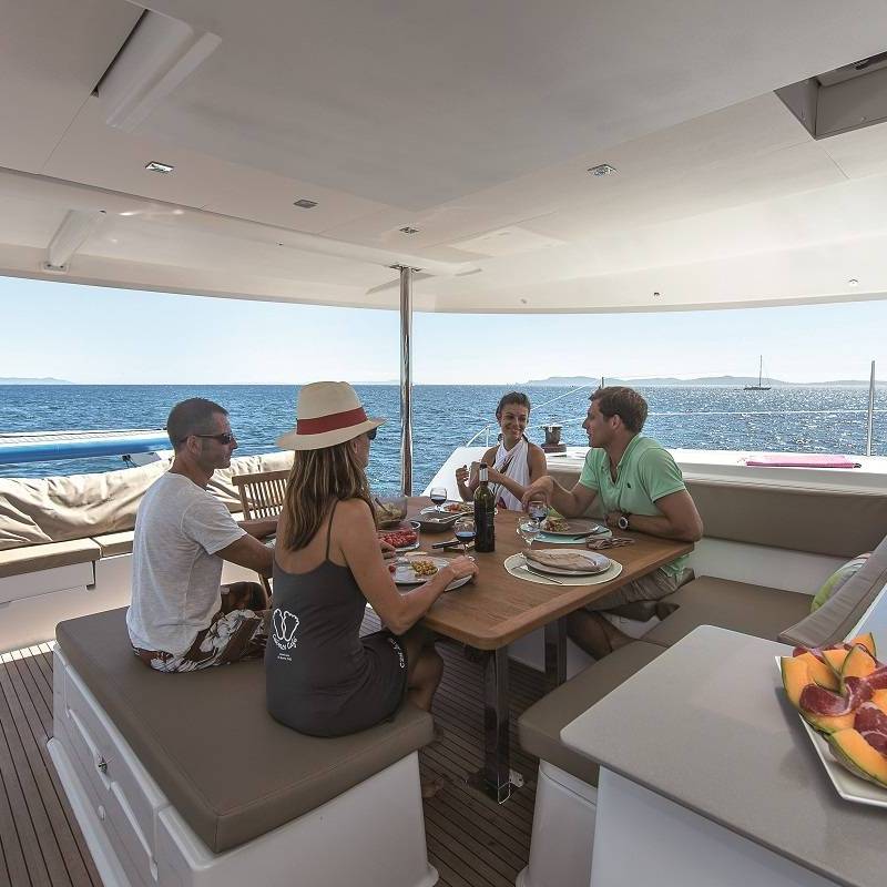 a group of people sitting at a table with food and water