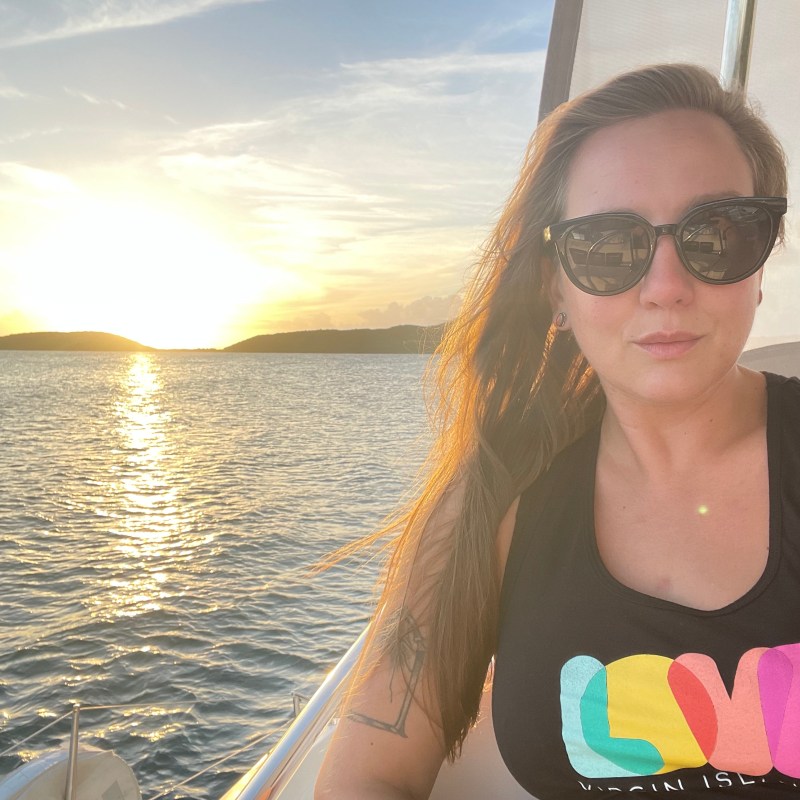 a woman wearing sunglasses standing in front of a body of water