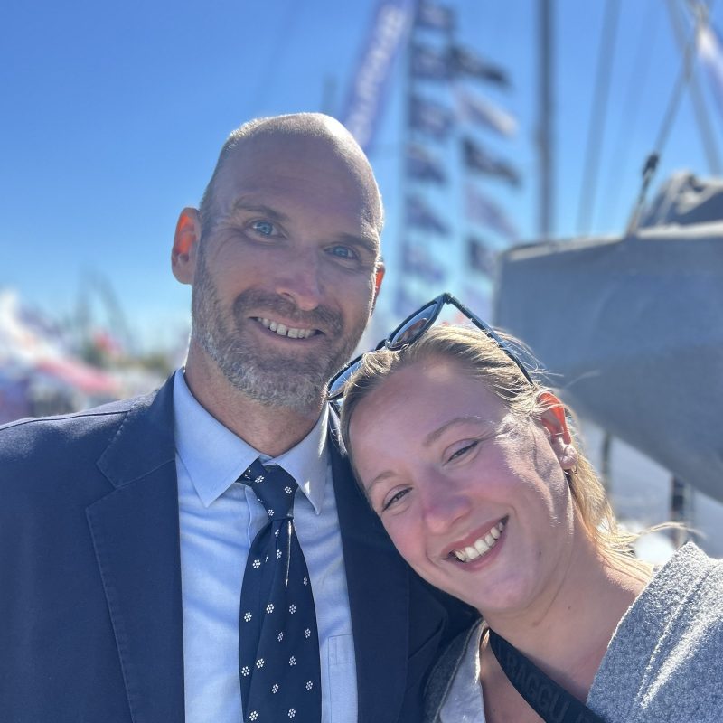 Two smiling people on a boat with a clear blue sky in the background.