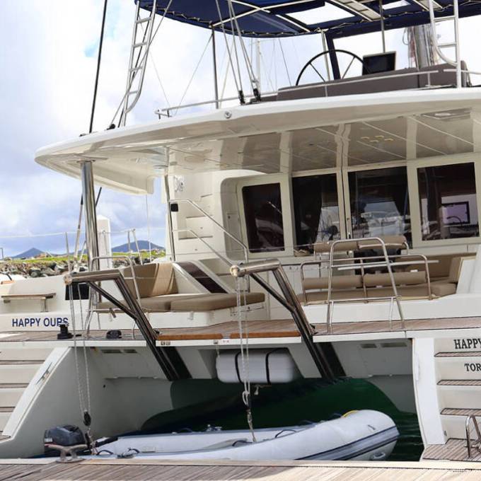 White yacht with upper deck and dinghy at the stern, moored at a dock.