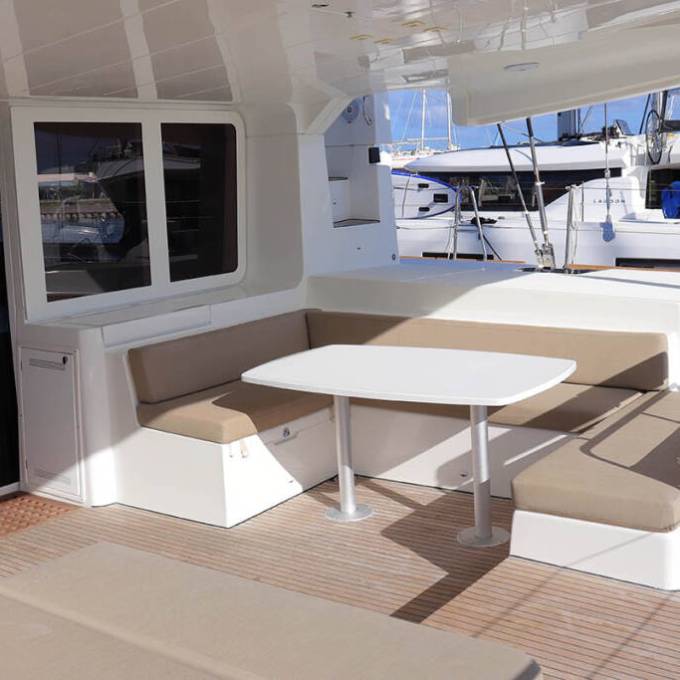 Outdoor seating area on a yacht with beige cushions and a white table.