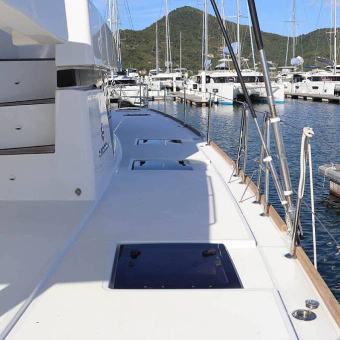 Side view of a boat deck in a marina with mountains and boats in the background.