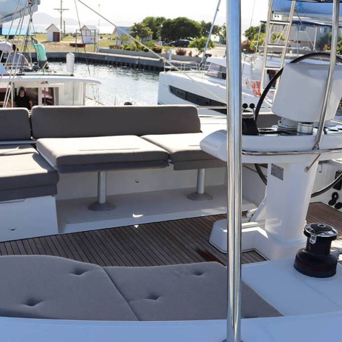 Sailboat cockpit with seating, steering wheel, and winches in a marina.