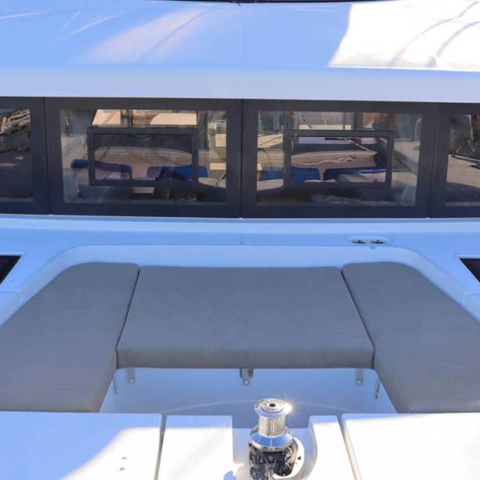 Boat deck with beige cushions and large windows facing forward.