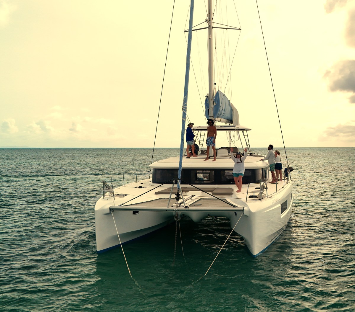 Go Sail Crew Go Sail Group of people on a catamaran sailboat in the ocean under a partly cloudy sky.