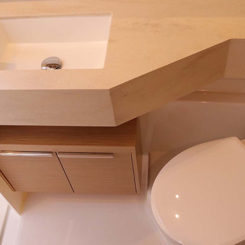 Compact bathroom with a sink and toilet, featuring wooden cabinet and chrome faucet.
