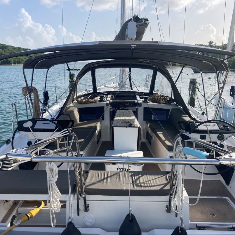 Sailboat cockpit with twin steering wheels and canopy, docked by the water.