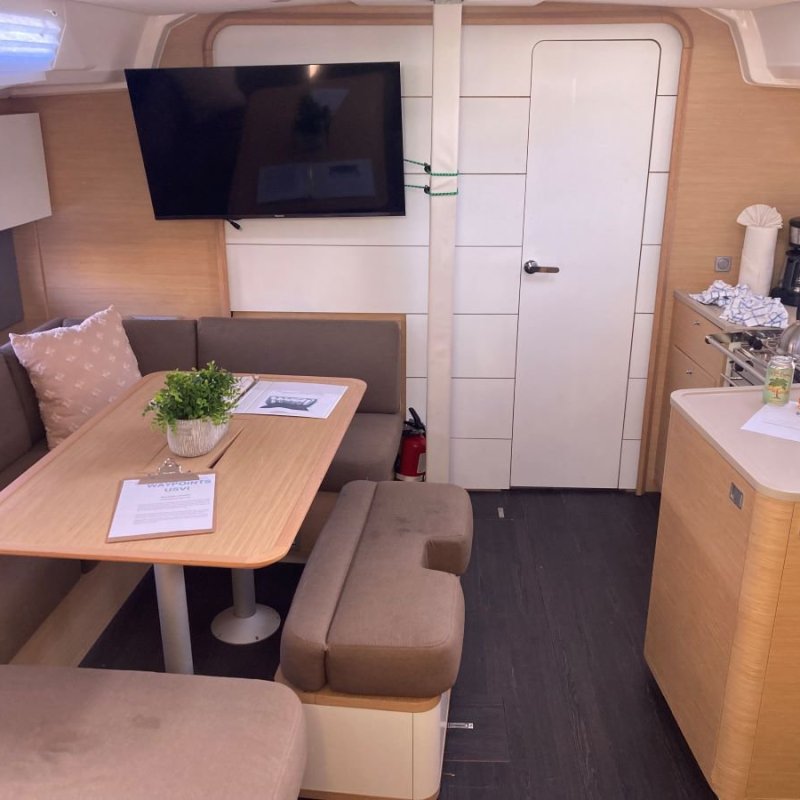 Interior of a boat with a dining area, TV, and kitchenette.