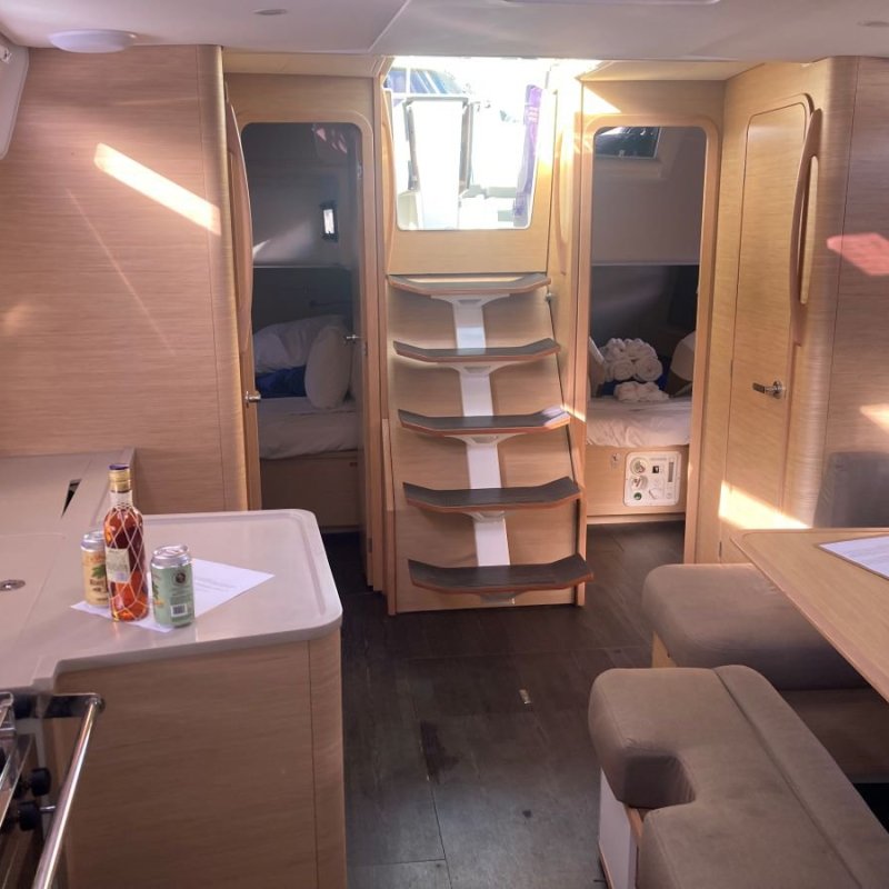 Interior of a yacht with kitchenette, seating area, and steps leading to sleeping quarters.