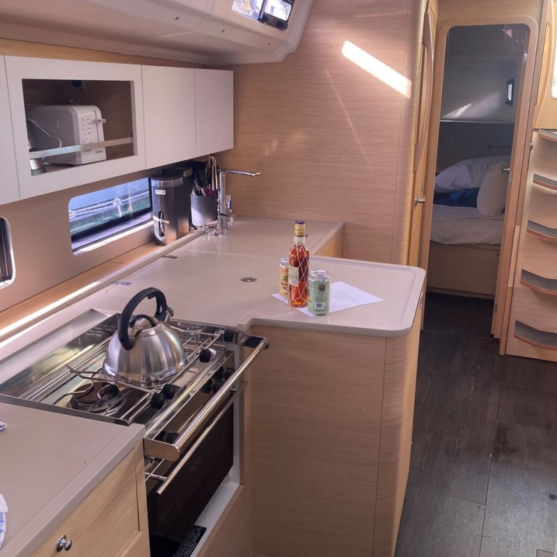 Interior of a yacht kitchen with a stove, kettle, and countertop with bottles.