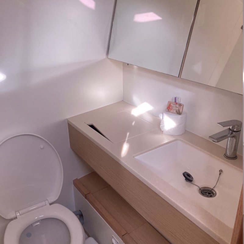 Small modern bathroom with a toilet, sink, and mirror cabinet.