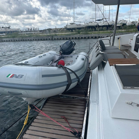 Inflatable boat tied to a docked yacht under a cloudy sky.