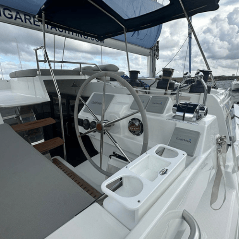 Sailboat cockpit with steering wheel and navigation equipment.