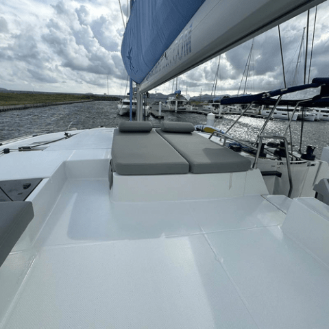 View of a sailboat deck with cushioned seating and visible marina in the background.