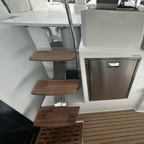 Wooden steps and a small refrigerator on a boat's deck.