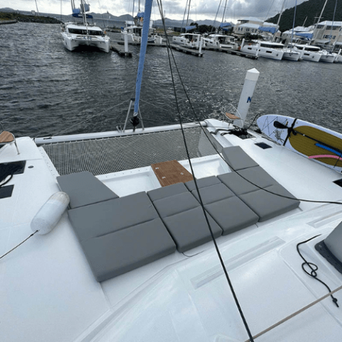 View of a boat's deck with gray cushions and moored yachts in a marina.