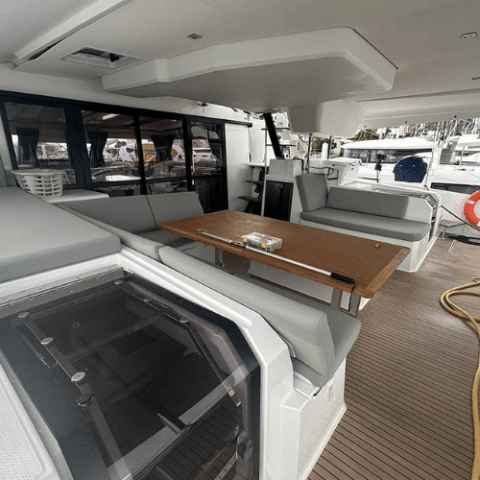Spacious yacht deck with seating, wooden table, and marina view.
