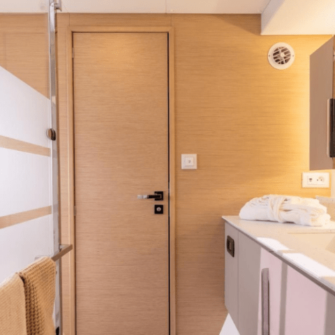 Modern bathroom with wooden door, towel on rack, and sink with folded towels.