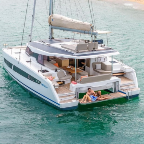 Couple relaxing on the deck of a catamaran yacht in calm, turquoise water.