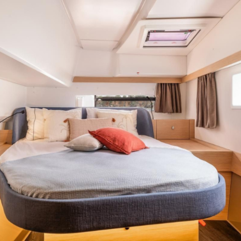 Cozy boat cabin with a round bed, pillows, and a small window.