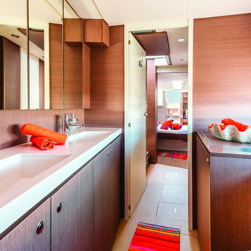 Modern bathroom with dual sinks, wooden cabinets, mirrors, and red towels.