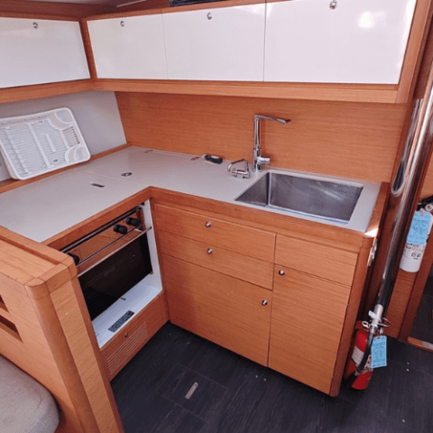 Wooden boat kitchen with sink, stove, and storage cabinets.