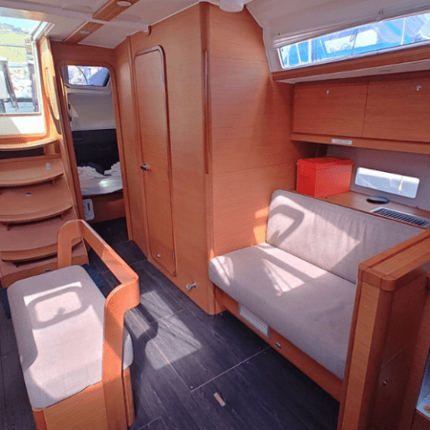 Interior of a boat cabin with wood paneling and grey cushions.