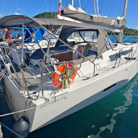 Docked sailboat with lifebuoy on railing under clear blue sky.