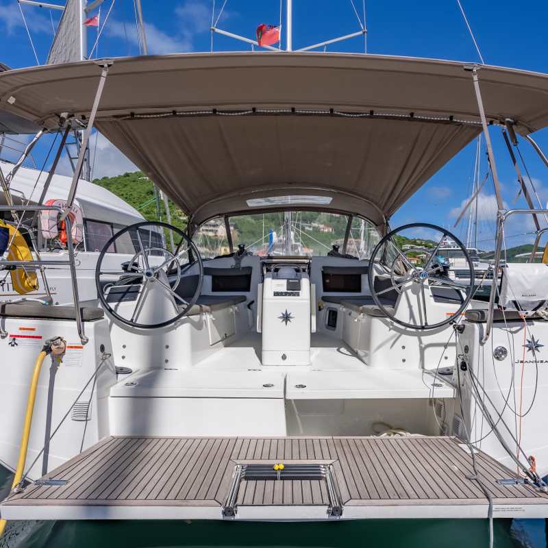 Stern view of a docked sailboat with dual steering wheels and a canopy.