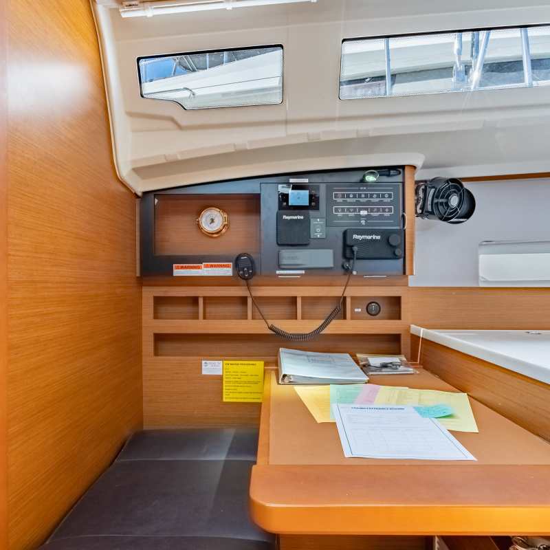Interior of a boat cabin with navigation equipment and a wooden desk.