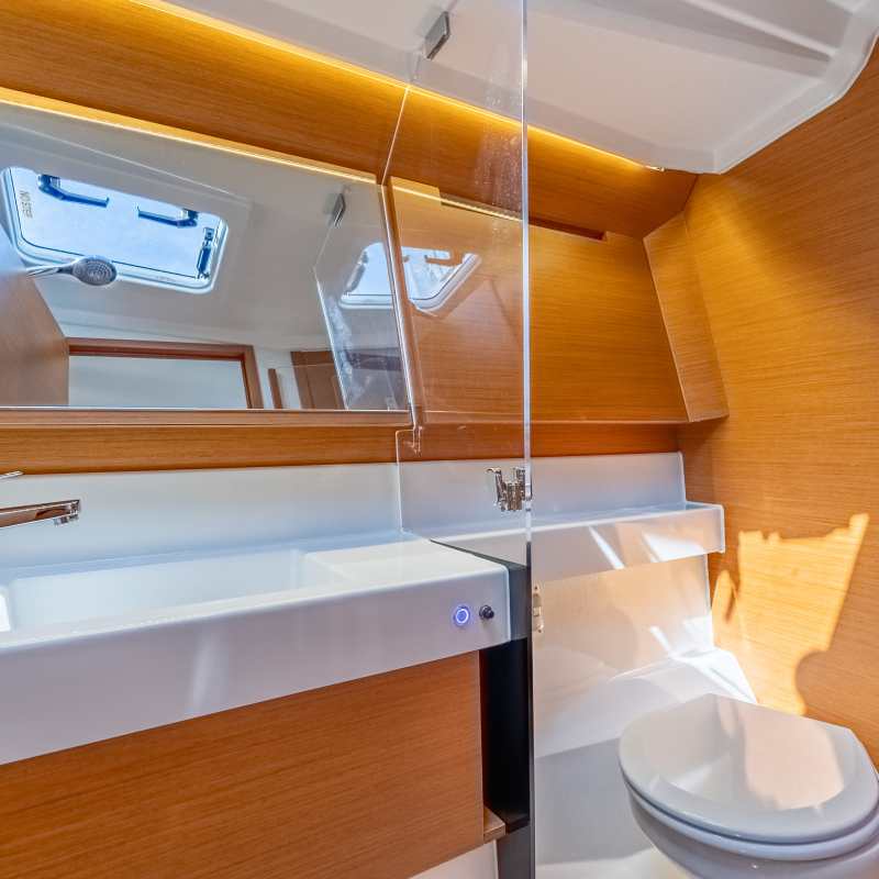 Modern yacht bathroom with wooden accents, sink, toilet, and mirror.